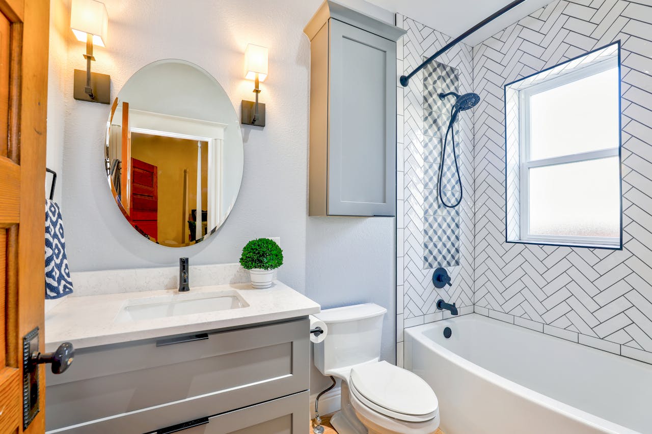 heros-img Elegant modern bathroom featuring chevron tiles, oval mirror, and sleek fixtures for a contemporary look.